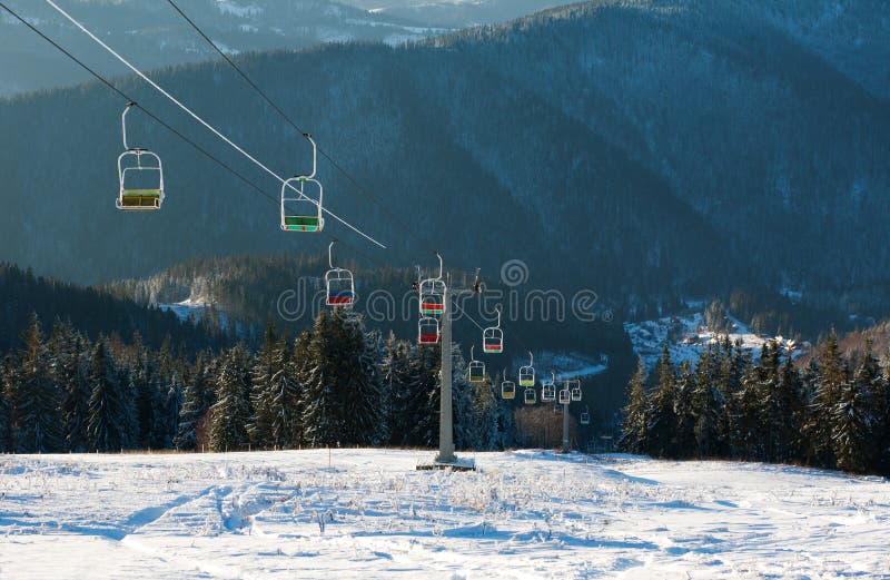 Ski Lift in Winter Snowy Mountains on Pine Forest Background Stock