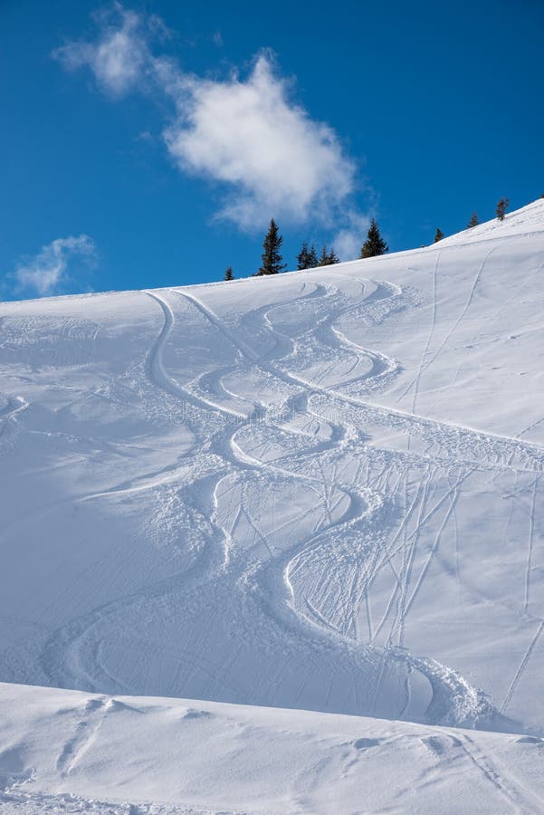Ski piste with deep powder snow and tracks from skiing or snowboard in the austrian alps