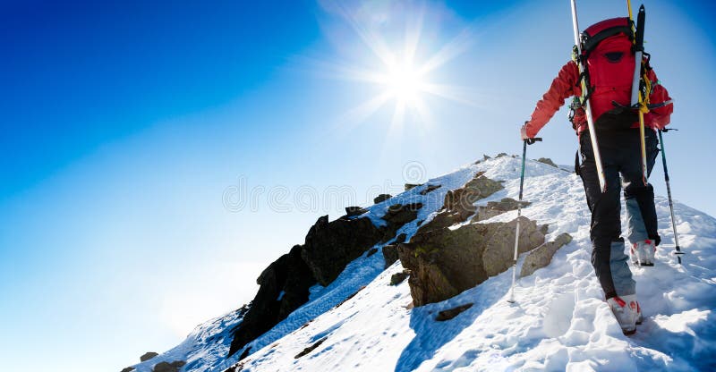 Skidar bergsbestigaren som går upp längs en brant snöig kant med sken