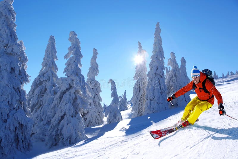 Skier skiing downhill in high mountains against sunset