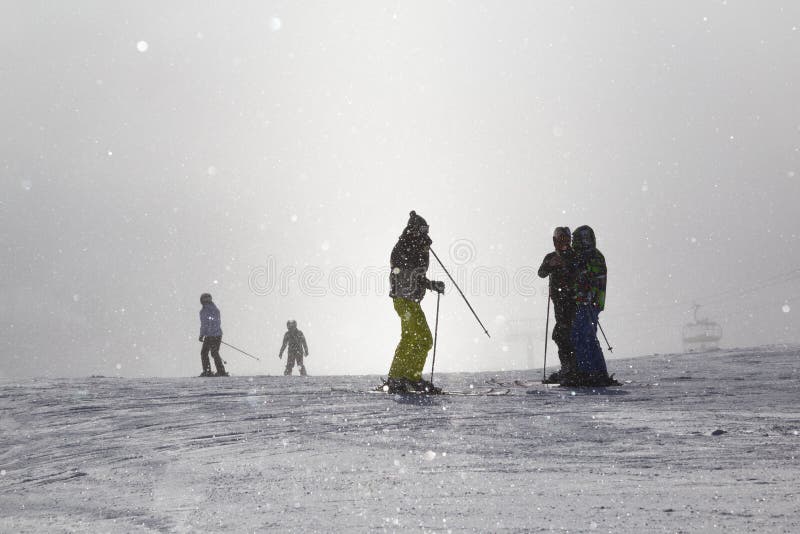 Skiers on ski slopes in fog.