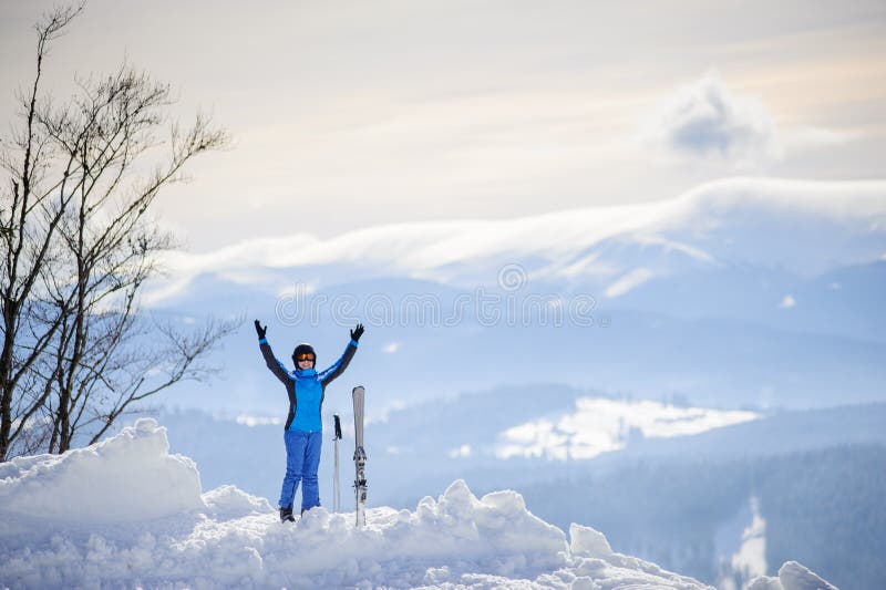 Happy skier standing on the top of the mountain with her arms lifted up against the background of beautiful winter mountains. Carpathian Mountains, Bukovel, Ukraine. Happy skier standing on the top of the mountain with her arms lifted up against the background of beautiful winter mountains. Carpathian Mountains, Bukovel, Ukraine