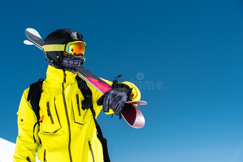 Skifahrer, der auf einer Steigung steht Mann in einer hellen Klage, im Sturzhelm und in der Maske im Skifahren soll Ski fahren Im stockfotografie Skifahrer, der auf einer Steigung steht Mann in einer hellen Klage, im Sturzhelm und in der Maske im Skifahren soll Ski fahren Im stockfotografie