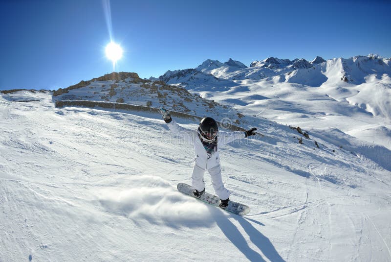 Skier skiing downhill on fresh powder snow with sun and mountains in background. Skier skiing downhill on fresh powder snow with sun and mountains in background