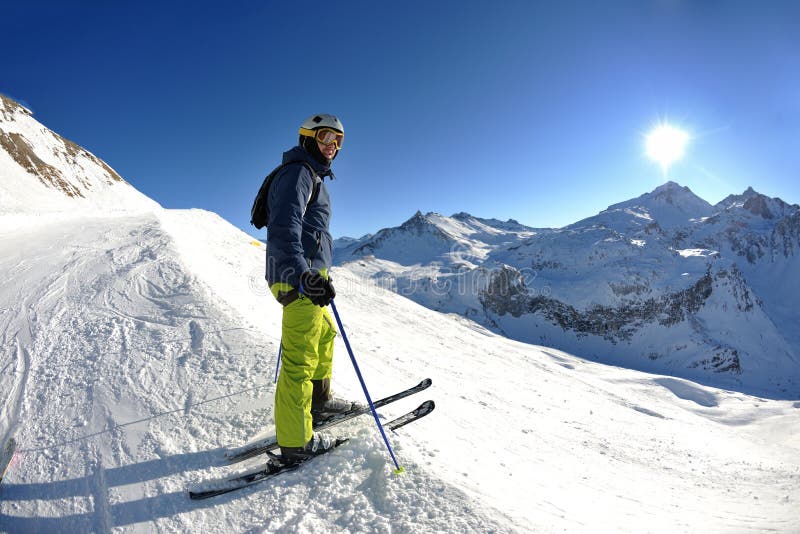 Skier skiing downhill on fresh powder snow with sun and mountains in background. Skier skiing downhill on fresh powder snow with sun and mountains in background