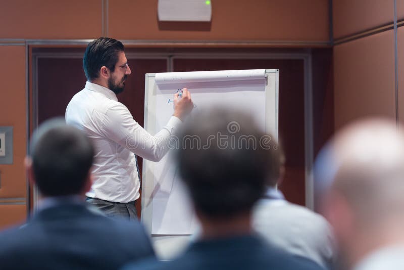 Skiled-Geschäftsmann Presenting ein Projekt zu seinem Arbeits-Team bei Generalversammlung Informal Company lizenzfreies stockbild Skiled-Geschäftsmann Presenting ein Projekt zu seinem Arbeits-Team bei Generalversammlung Informal Company lizenzfreies stockbild