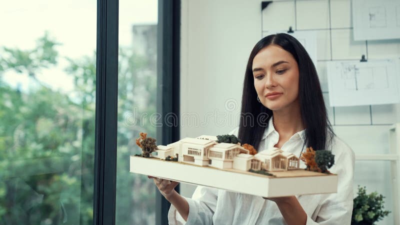 Skilled caucasian architect lift house model to check mistake point. Immaculate. Close up of skilled young beautiful caucasian architect lift house model left