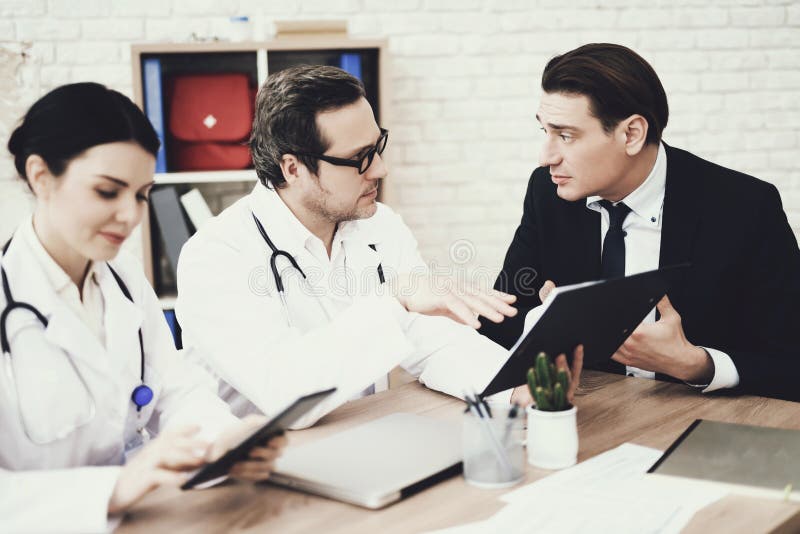 Skilled doctor advises businessman in medical office. Consultation with attending physician. stock image Skilled doctor advises businessman in medical office. Consultation with attending physician. stock image