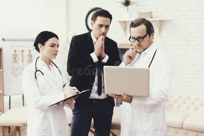 Skilled doctor shows on laptop results of medical examination of successful businessman in office. stock photos Skilled doctor shows on laptop results of medical examination of successful businessman in office. stock photos