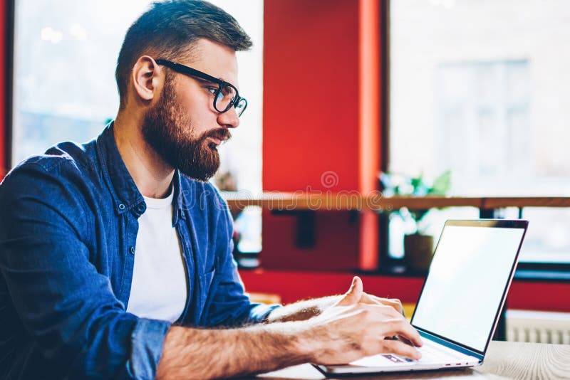 Skilled hipster guy working remotely with startup project on laptop device with copy space stock image