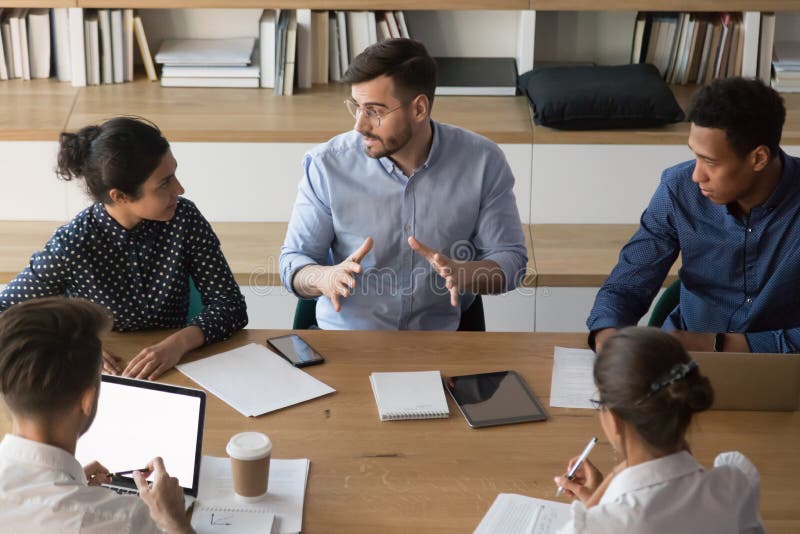 Skilled male manager talking to diverse business people at meeting