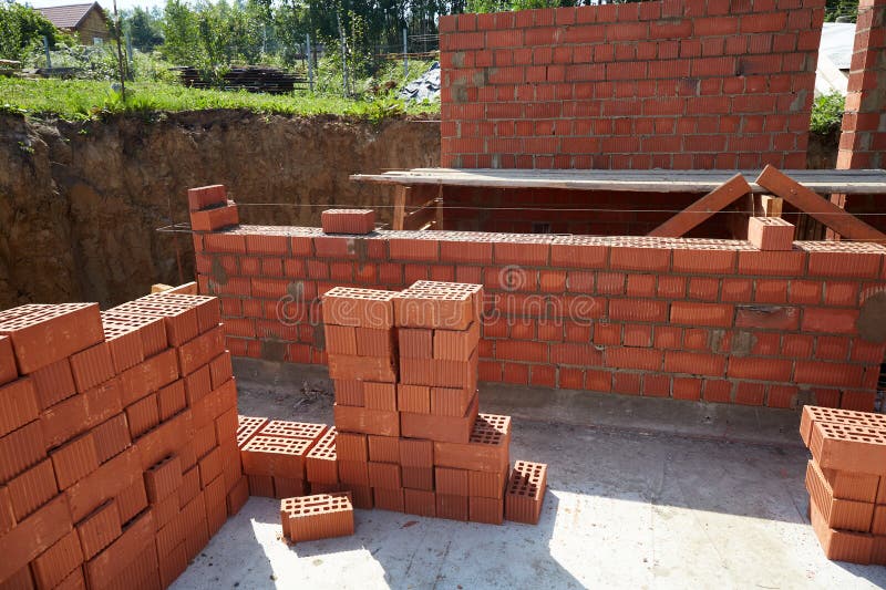 Skilled workers are constructing a brick wall with red bricks at a construction site. stock images