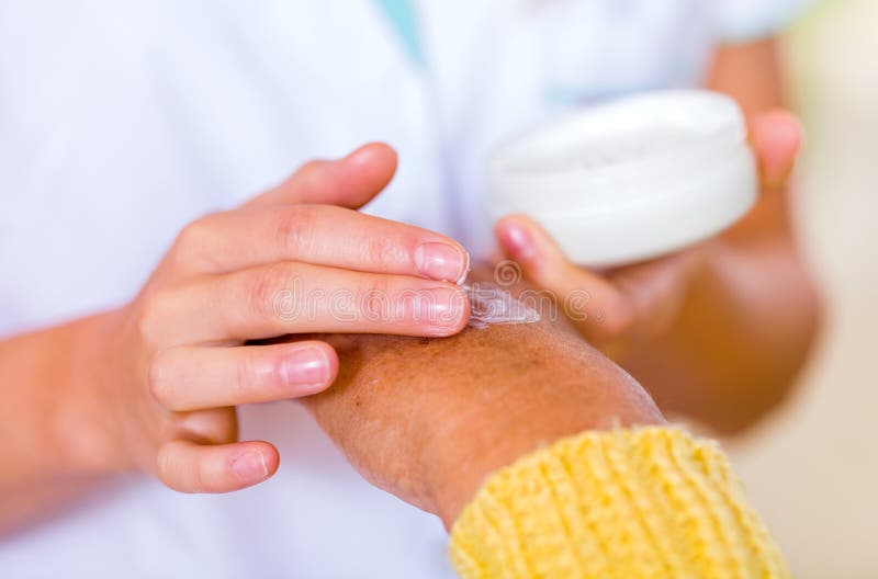 The carer rubbing the elderly woman's hand with cream. The carer rubbing the elderly woman's hand with cream