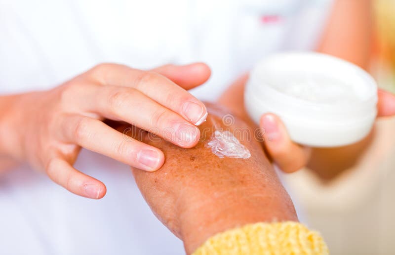 The carer rubbing the elderly womans hand with cream. The carer rubbing the elderly womans hand with cream