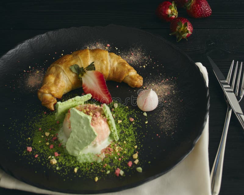 Skiva av äpplestrudel med en skopa av vaniljglass på en svart platta, på en träsvart tabell som dekoreras med maräng och arkivbilder Skiva av äpplestrudel med en skopa av vaniljglass på en svart platta, på en träsvart tabell som dekoreras med maräng och arkivbilder