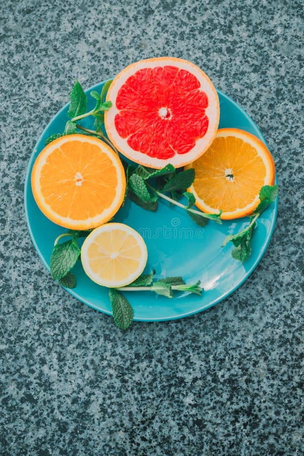 Skivad citron, apelsin, grapefrukt och mintkaramell på en blå platta, vitaminer, citrus i minimalismstil, popkonst royaltyfri foto Skivad citron, apelsin, grapefrukt och mintkaramell på en blå platta, vitaminer, citrus i minimalismstil, popkonst royaltyfri foto