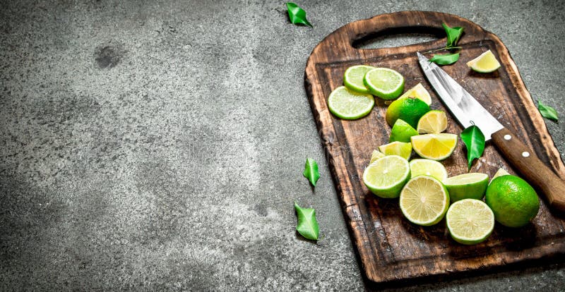 Skivade nya limefrukter på en skärbräda med en kniv royaltyfri fotografi Skivade nya limefrukter på en skärbräda med en kniv royaltyfri fotografi