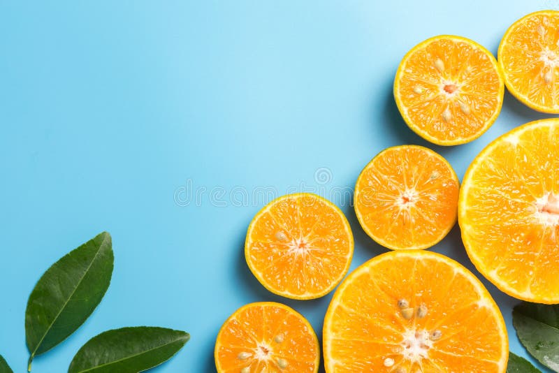 Skivade orange frukter med sidor på blå bakgrund royaltyfria foton