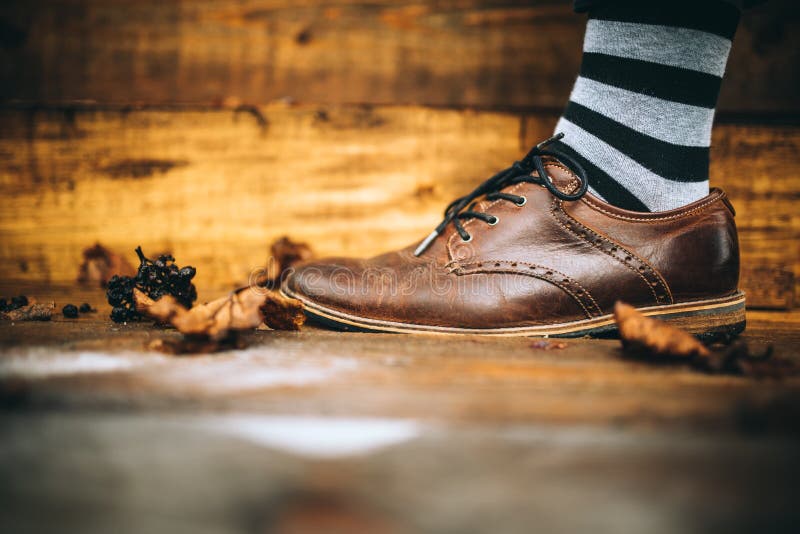 Sko för manmodebrunt på wood bakgrund med randiga sockor arkivfoto Sko för manmodebrunt på wood bakgrund med randiga sockor arkivfoto