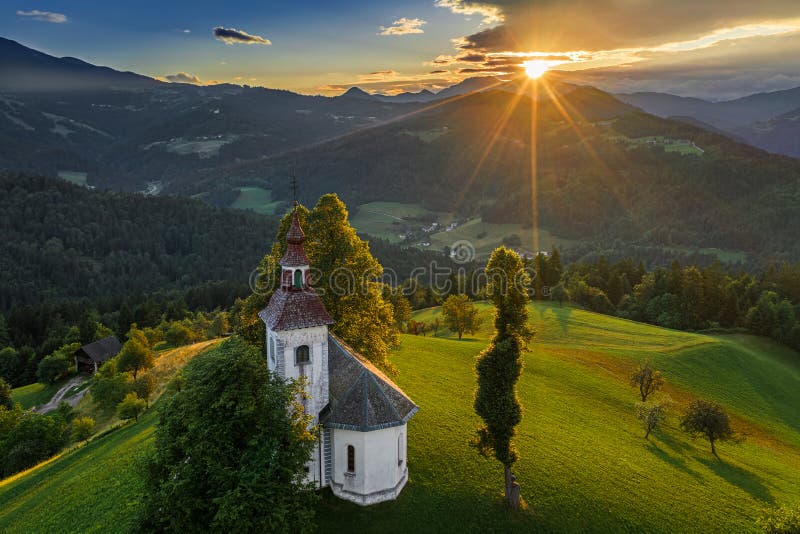 Skofja Loka, Slovenien - den flyg- sikten av den härliga bergstoppet Sveti Tomaz Saint Thomas kyrktar med en fantastisk solnedgån arkivbild Skofja Loka, Slovenien - den flyg- sikten av den härliga bergstoppet Sveti Tomaz Saint Thomas kyrktar med en fantastisk solnedgån arkivbild