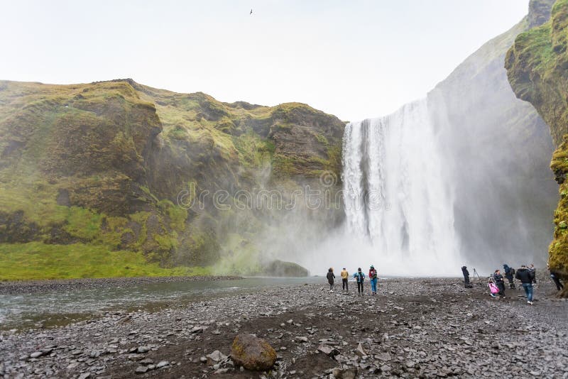 People at the bottom of Skogafoss waterfall