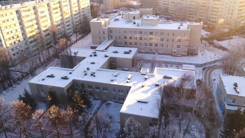 Skolbyggnad med snötäckt tak mellan bostadsområde