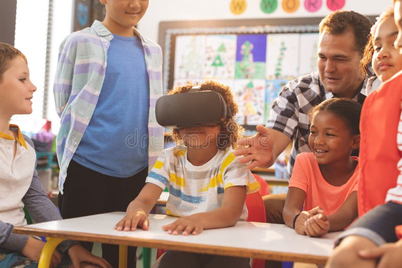 Skolpojke som använder virtuell verklighethörlurar med mikrofon med hans klasskompis och lärare