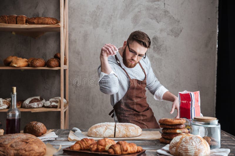 Skoncentrowanego mężczyzna piekarniana pozycja przy piekarnią blisko chleba