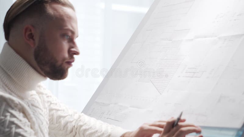 Skoncentrowany architekt pracuje na poddaszu za pomocą tablicy rysunkowej. miejsce pracy młodego inżyniera w nowoczesnym biurze. zbiory