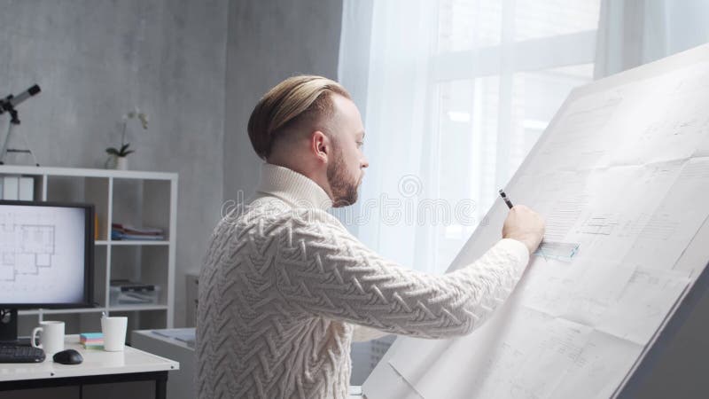 Skoncentrowany architekt pracuje na poddaszu za pomocą tablicy rysunkowej. miejsce pracy młodego inżyniera w nowoczesnym biurze. zdjęcie wideo