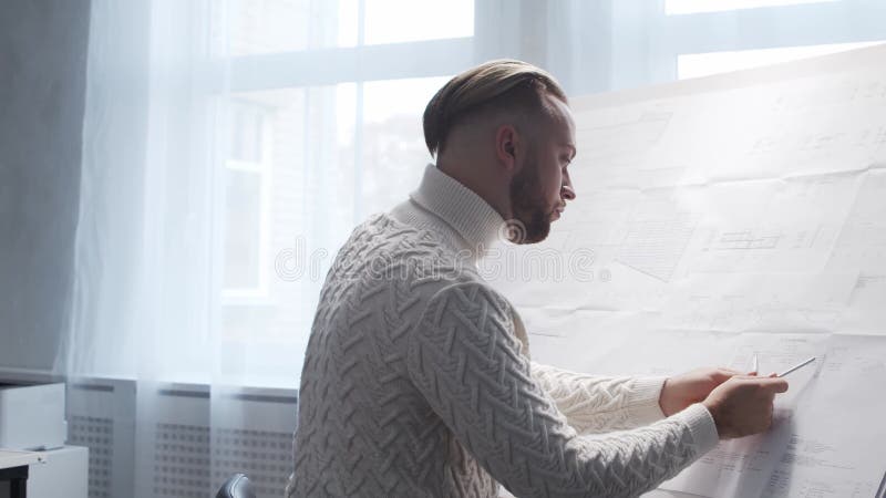 Skoncentrowany architekt pracuje na poddaszu za pomocą tablicy rysunkowej. miejsce pracy młodego inżyniera w nowoczesnym biurze. zbiory