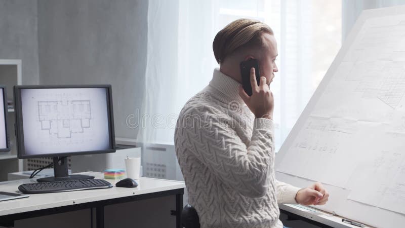 Skoncentrowany architekt pracuje na poddaszu za pomocą tablicy rysunkowej. miejsce pracy młodego inżyniera w nowoczesnym biurze. zdjęcie wideo