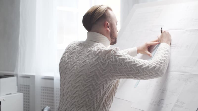 Skoncentrowany architekt pracuje na poddaszu za pomocą tablicy rysunkowej. miejsce pracy młodego inżyniera w nowoczesnym biurze. zbiory wideo