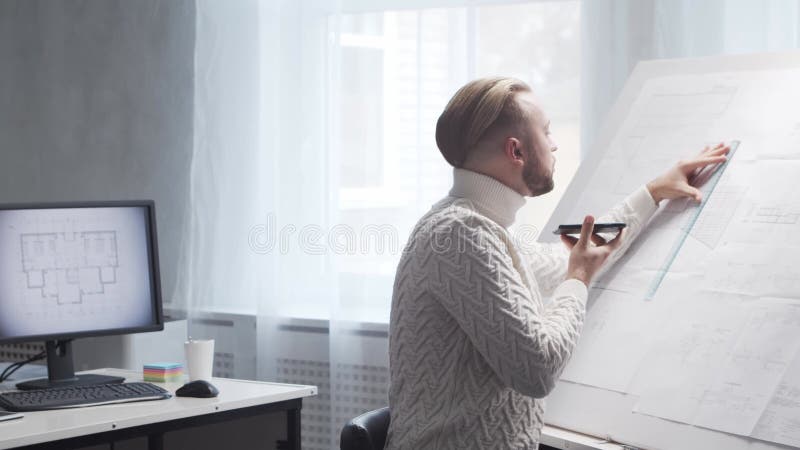 Skoncentrowany architekt pracuje na poddaszu za pomocą tablicy rysunkowej. miejsce pracy młodego inżyniera w nowoczesnym biurze. zdjęcie wideo
