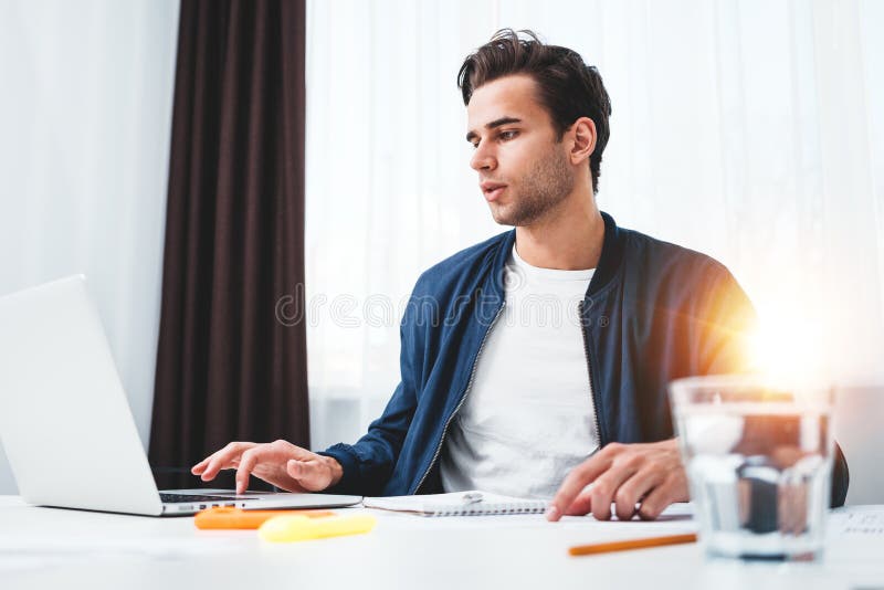 Skoncentrowany kierownik pracuje na laptopie i czytelniczej informacji w nowożytnym spale biurze obrazy stock Skoncentrowany kierownik pracuje na laptopie i czytelniczej informacji w nowożytnym spale biurze obrazy stock