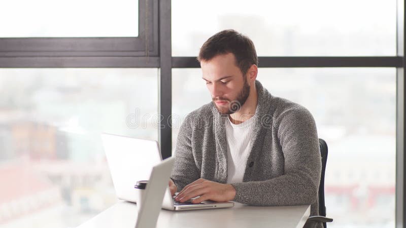 Skoncentrowany, mÅ‚ody urzÄ™dnik w okularach, ktÃ³ry patrzy na laptopa