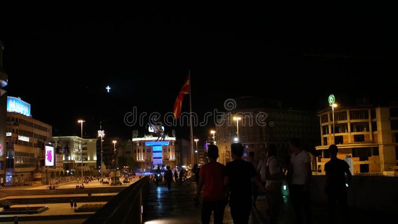SKOPJE MACEDONIA - JULIO DE 2015: Alexander la gran estatua, la bandera macedónica y la cruz grande