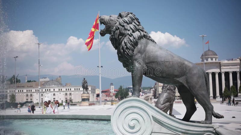 SKOPJE MACEDONIA - 2015, manifestazione dell'acqua e statue del leone sotto il monumento di Alessandro Magno con la bandiera mace