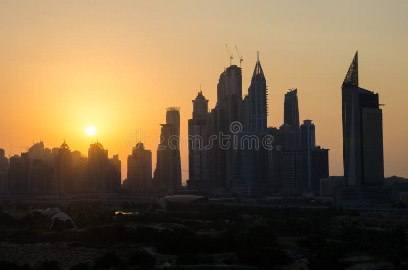 Skott för kontur för cityscape för solnedgång för Dubai marina dammigt från gräsplangolfbanan Gräsplanerna - dubai arkivbild Skott för kontur för cityscape för solnedgång för Dubai marina dammigt från gräsplangolfbanan Gräsplanerna - dubai arkivbild