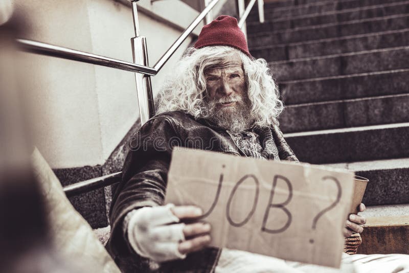 Necessary request. Close up of old troubled almsman with handwritten sign asking stranger about any job for him. Necessary request. Close up of old troubled almsman with handwritten sign asking stranger about any job for him.