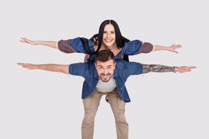 Skraj jubel för det fulla fotoet för längdkroppformatet låtsar hon som är hennes honom honom hans damgrabbvingar, ridtur på axlar arkivbilder Skraj jubel för det fulla fotoet för längdkroppformatet låtsar hon som är hennes honom honom hans damgrabbvingar, ridtur på axlar arkivbilder