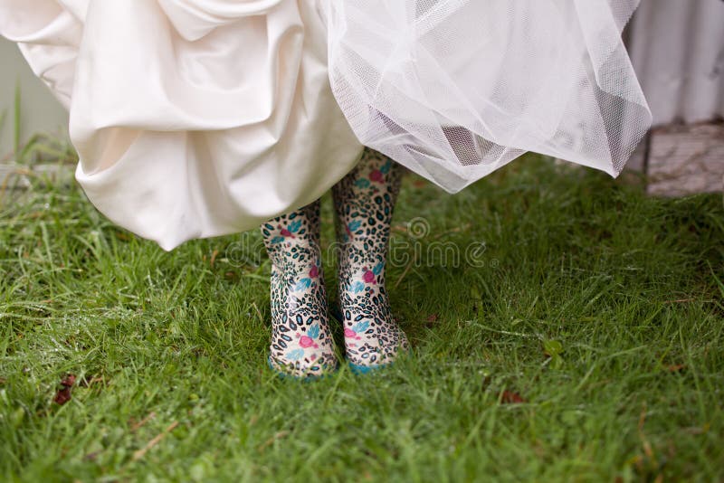 A Bride lifts up her wedding dress to reveal funky colorful gumboots underneath. A Bride lifts up her wedding dress to reveal funky colorful gumboots underneath