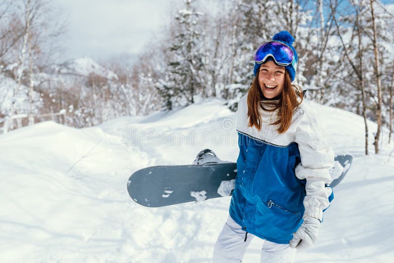 Skratt lycklig flicka med snöskiva och bakgrund av berg och snöträd