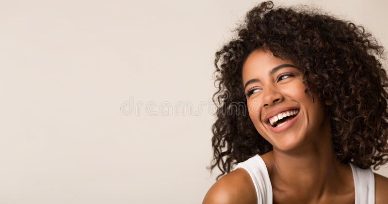 Skratta afrikansk amerikankvinnan som ser bort på ljus bakgrund