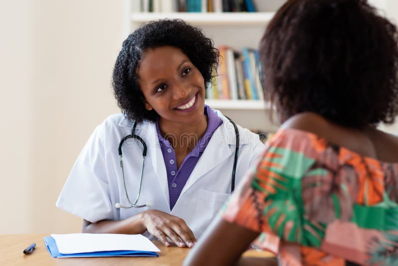 Skratta den kvinnliga doktorn för afrikansk amerikan med patienten royaltyfria bilder