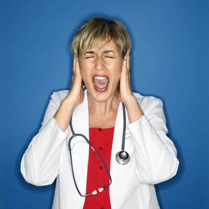 Caucasian female doctor holding hands to ears and screaming. Caucasian female doctor holding hands to ears and screaming.