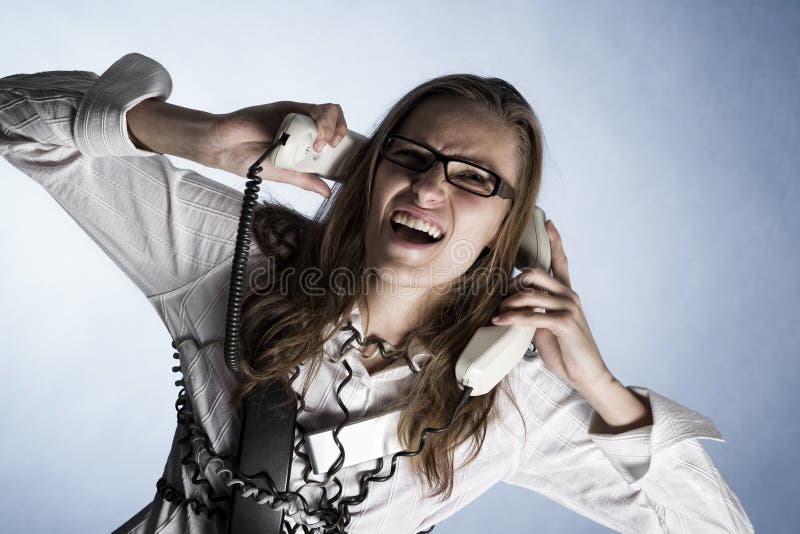 Furious telephonist in call center wrapped with phone cables being overstrained with work, isolated on blue background. Furious telephonist in call center wrapped with phone cables being overstrained with work, isolated on blue background.