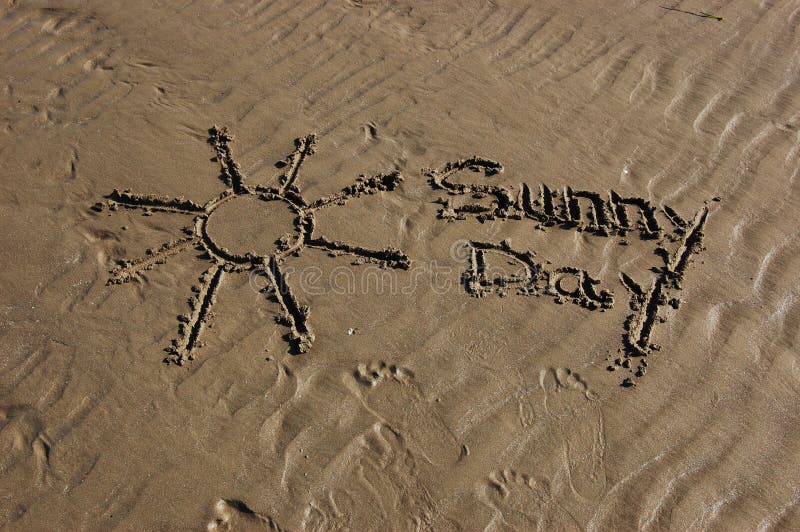 Words sunny day and sun symbol written in the beach sand; conceptual for weather forecast or holiday. Words sunny day and sun symbol written in the beach sand; conceptual for weather forecast or holiday
