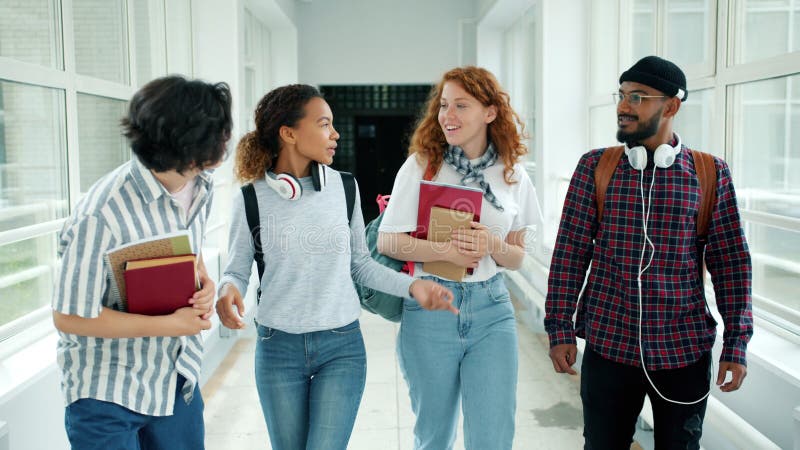 Skroliga studenter som talar med böcker i högskolan visar upp tummen stock video