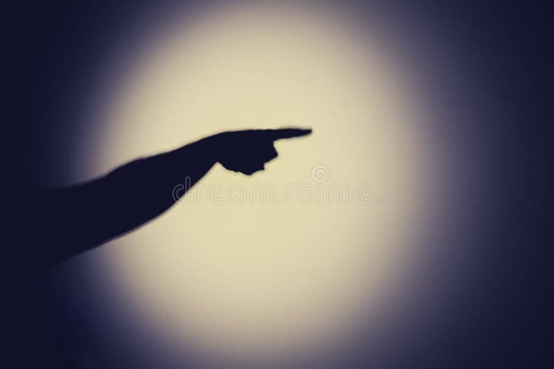 Shadow of a hand from the night light of a flashlight on a white wall. Dark silhouette of a man hands from the light of a lamp-. Shadow of a hand from the night light of a flashlight on a white wall. Dark silhouette of a man hands from the light of a lamp-